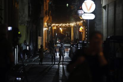 Personas caminan por una calle adornada con luces de navidad este domingo, 21 de diciembre de 2025, en La Habana (Cuba).