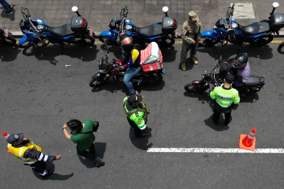 Agentes de policía registran a motociclistas en un puesto de control después de que el gobierno declarara el estado de emergencia en Lima el 22 de octubre de 2025.
