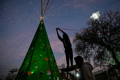 Un hombre decora un árbol de Navidad durante las celebraciones de la Nochebuena en Islamabad el 24 de diciembre de 2025.