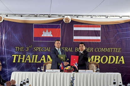 Tea Seiha (i) y Natthaphon Narkphanit (i), los ministros de Defensa de Camboya y Tailandia, respectivamente, intercambian el acuerdo firmado de cese al fuego.