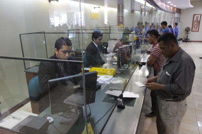 Clientes son atendido en las ventanillas de un banco de Ecuador.