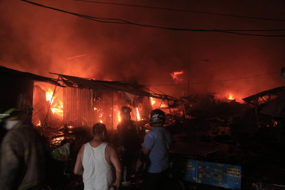 Cuerpo de Bomberos de Honduras trabajan junto a ciudadanos para controlar  un incendio provocado en un puesto de venta de pólvora en San Pedro Sula (Honduras).