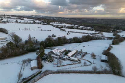 La imagen muestra un paisaje rural cubierto de nieve y edificios agrícolas en el Reino Unido durante una importante ola de frío a inicios de 2026.