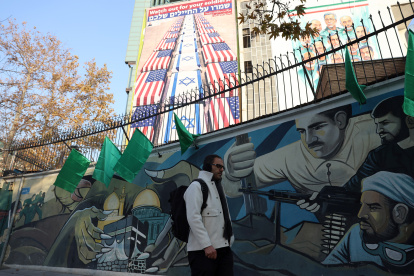 Un hombre iraní camina junto a una valla publicitaria antiestadounidense e israelí con un mensaje del secretario del Consejo Supremo de Seguridad Nacional, Ali Larijani, que dice "Cuidado con sus soldados".