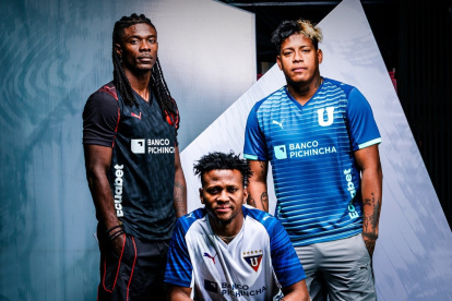 Ricardo Adé (I), Michael Estrada (C) y Richard Mina (D) posan con la nueva indumentaria de Liga de Quito para el 2026.