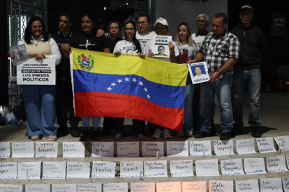 Familiares de presos políticos en Venezuela sostienen carteles en una vigilia, afuera de El Helicoide en Caracas.