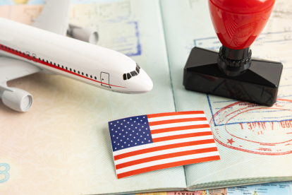 Referencial. Pasaporte con sellos de entrada y salida, junto a una bandera de EE.UU. y un avión en miniatura, simboliza las tensiones migratorias entre Tailandia y Estados Unidos.