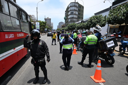 Agentes policiales registran a motociclistas en un puesto de control después de que el gobierno declarara el estado de emergencia en Lima.