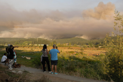 Personas observan el humo tras incendios forestales este domingo, en la comuna de Penco, Concepción (Chile).