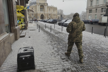 Un soldado ucraniano pasa por delante de un generador de diésel con la ópera de Odesa de fondo.