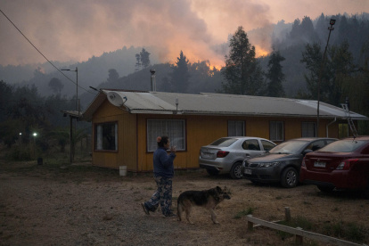 Una mujer camina cerca a un incendio forestal en la comuna de Chaimávida, en Concepción a unos 491 km aproximadamente de Santiago (Chile).