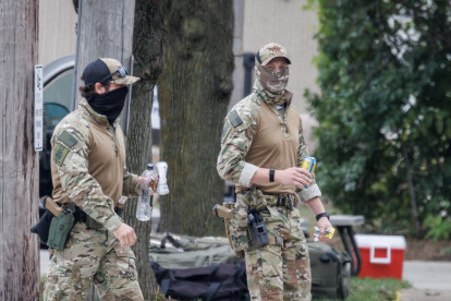 Agentes enmascarados del Servicio de Inmigración y Control de Aduanas (ICE) caminando frente a la entrada del centro de detención (Estados Unidos).