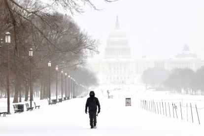 Un hombre camina por el National Mall mientras cae nieve en Washington, DC, el 25 de enero de 2026.