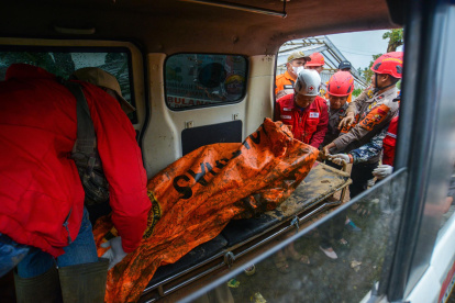 Los rescatistas llevan restos de una víctima en una zona afectada por un deslizamiento de tierra en la aldea de Pasirlangu, Indonesia, el 25 de enero de 2026.