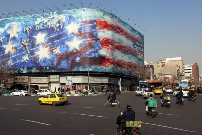 Los vehículos circulan cerca de una enorme valla publicitaria antiestadounidense colgada en la plaza Enqelab en Teherán, Irán, el 27 de enero de 2026.