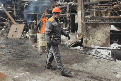 Andriy, un electricista, cerca de los barriles con leña encendida, instalados para calentar la sección dañada de una planta de energía térmica en Ucrania después de los ataques rusos.