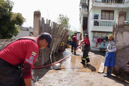 La adulta mayor afectada observa a los miembros del Cuerpo de Bomberos realizar su trabajo.