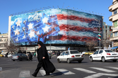 Una mujer iraní con velo camina cerca de un enorme cartel antiestadounidense colgado en la plaza Enqelab en Teherán, el sábado 31 de enero de 2026.