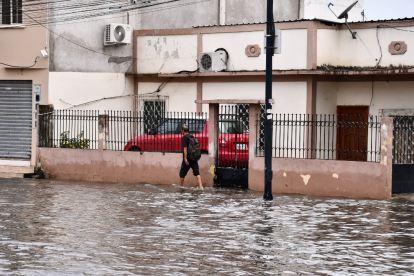 Un ciudadano camina entre calles anegadas en Machala tras las intensas lluvias que provocaron inundaciones en varios sectores