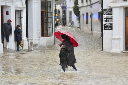 Una vecina de Grazalema (Cádiz) camina por una calle inundada debido a las intensas lluvias.