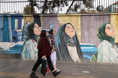 Mural. Mujeres pasan frente a un mural representativo, en Tehran.
