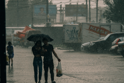 Referencial. Ciudadanos se resguardan bajo paraguas mientras las fuertes lluvias cubren las calles, en medio de la alerta emitida por el Inamhi para varias zonas del país.