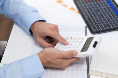 Referencial.Una persona revisa documentos financieros y utiliza una calculadora, en el marco de los requisitos para acceder al crédito Emprende Violeta de 500 dólares.