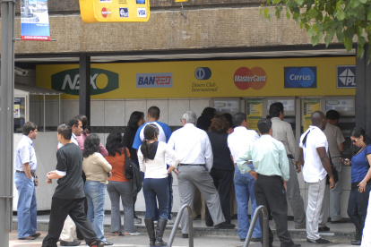 Un grupo de personas realizan fila en cajeros automáticos de una entidad bancaria en Quito.