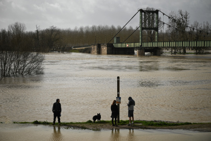 Personas en un sendero rodeado de una zona inundada en Marmande, suroeste de Francia, el 12 de febrero de 2026, mientras la tormenta Nils provoca inundaciones excepcionales a lo largo del río Garona.