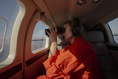 El Coordinador Táctico de la Iniciativa Piloto Humanitaria (HPI) escanea el océano con un par de binoculares durante una misión de patrullaje el 22 de enero de 2025.