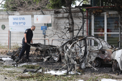 Un policía israelí inspecciona los restos de un vehículo incendiado después de que Israel interceptara un misil balístico de Irán, este domingo 15, en Tel Aviv.