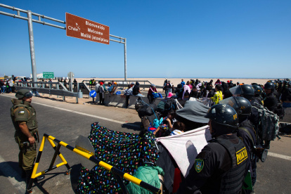 Policías peruanos (d) y chilenos vigilan a cientos de migrantes varados en la frontera, en Arica (Chile).