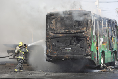 Un integrante del Cuerpo de Bomberos de Guadalajara intenta apagar un vehículo incendiado este domingo 22 de febrero, en esa ciudad mexicana.