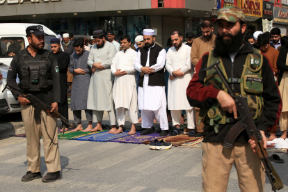 Oficiales de seguridad y musulmanes civiles en una calle de Peshawar, en Pakistán.