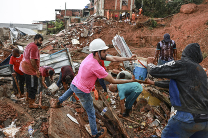 Personas ayudan en labores de rescate y remoción de escombros en una zona afectada por fuertes lluvias este martes, en Juiz de Fora (Brasil).