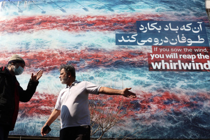 Iraníes conversan frente a un cartel antiestadounidense en Teherán, Irán, el 25 de febrero de 2026.