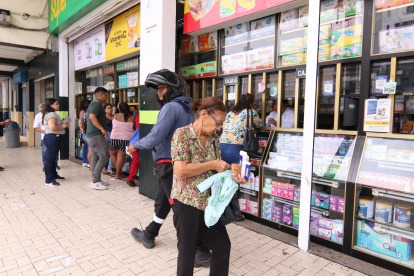 Una mujer revisa la factura de la medicina que ha comprado sorprendida de que ahora cuesta más.