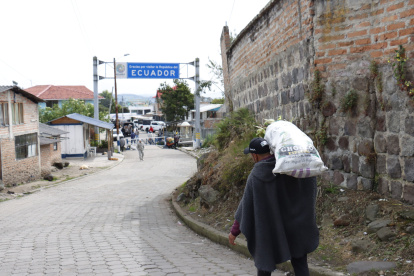 Un hombre carga un costal con productos agrícolas y lo atraviesa hasta cruzar el paso fronterizo.