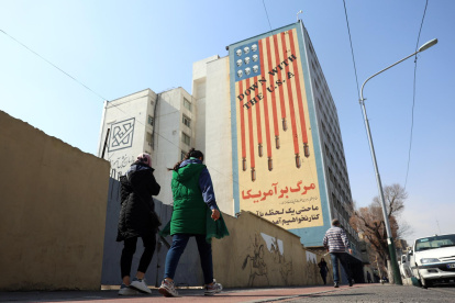 Iraníes caminan junto a un mural antiestadounidense en Teherán, Irán, el 23 de febrero de 2026.