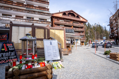 Velas y flores colocadas en la entrada del bar "Le Constellation", con sus ventanas cubiertas por paneles de MDF y selladas por la Policía, en Crans-Montana, este 8 de febrero.
