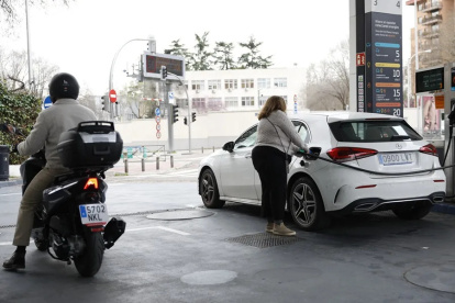 Una mujer llena de combustible su carro.