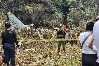 Varias personas y soldados se encuentran junto a los restos de un avión Hércules de la Fuerza Aérea que se estrelló durante el despegue, en Puerto Leguizamo (Colombia), el 23 de marzo de 2026.