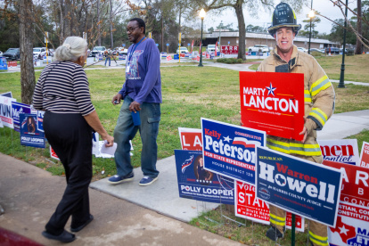 Personas caminan junto a anuncios de candidatos durante la jornada electoral en la entrada del Centro Comunitario este martes, en Houston (Estados Unidos).