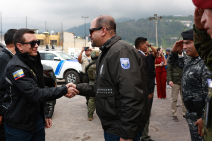 El presidente Daniel Noboa estrecha la mano del ministro del Interior, John Reimberg, durante un acto oficial acompañado por personal militar.
