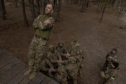 Entrenamiento. Un recluta ucraniano cae al suelo mientras sus compañeros se preparan para atraparlo durante un entrenamiento militar básico.