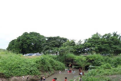 Familias acuden a un riachuelo en la vía a la costa para bañarse.