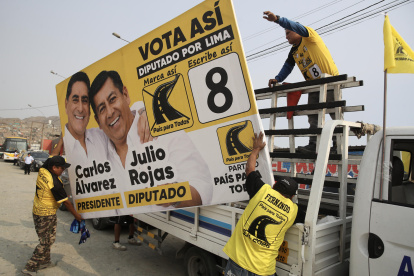Personas sostienen una valla publicitaria del candidato a la Presidencia de Perú Carlos Álvarez y el diputado Julio Rojas este sábado, en Lima (Perú).