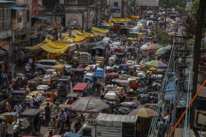Personas y vehículos transitan por una calle congestionada en un mercado mayorista del casco antiguo de Nueva Delhi.