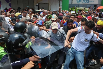 Personas exigen aumentos salariales mientras se enfrentan con integrantes de la policía en una manifestación este jueves, en Caracas (Venezuela).