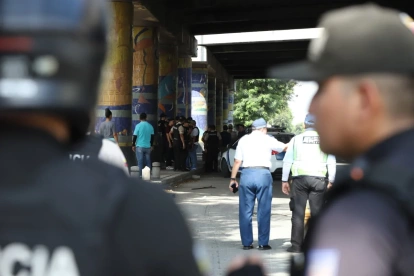 Policías y agentes de tránsito inspeccionan la escena del ataque armado en la vía a la costa, en Guayaquil, donde dos uniformados fueron asesinados tras una persecución desde Santa Elena.
